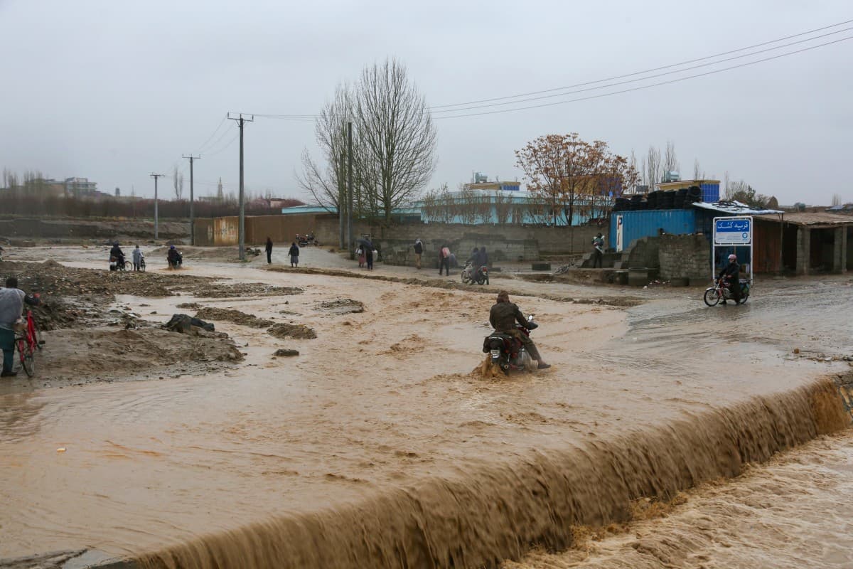 An Afghan motorist wades across a flooded road during rainfall in Ghazni Province on April 1, 2026. (AFP)