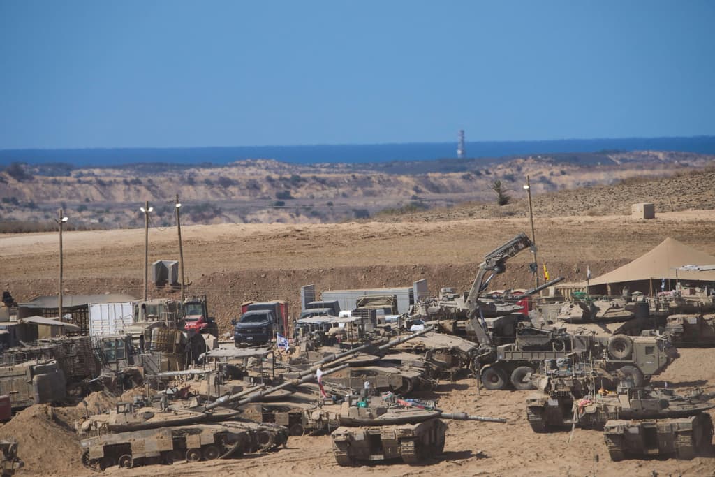 Israeli soldiers work on their tanks at a gathering point on the border with the Gaza Strip, in southern Israel, Saturday, Oct. 11, 2025 after Israel and Hamas have agreed to a pause in their war and the release of the remaining hostages. (AP Photo/Ariel