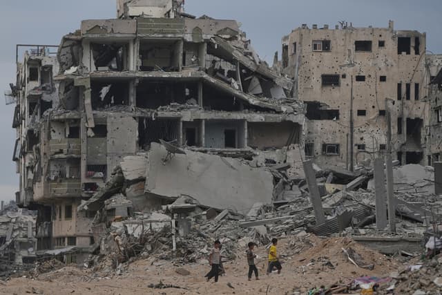 Palestinian children walk past destroyed buildings in the Shati refugee camp in Gaza City, Sunday, Oct. 12, 2025, after Israel and Hamas agreed to a pause in their war and the release of the remaining hostages. (AP)