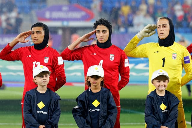 Iranian players, goalkeeper Raha Yazdani (R), Melika Motevalli (C) and Fatemeh Amineh, salute during the national anthem before the AFC Women's Asian Cup Australia 2026 football match between Iran and Philippines in Gold Coast on March 8, 2026. (AFP)