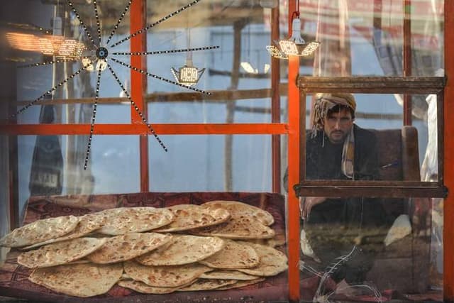 An Afghan vendor selling bread waits for customers at a bakery in the Fayzabad district of Badakhshan province on November 11, 2025. (AFP)