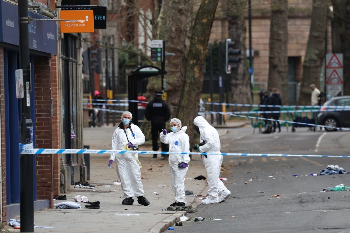 Police forensic officers work amongst a variety of personal items seen covering the road, inside a cordon set up on Friar Gate in central Derby, central England, on March 29, 2026, following an incident the night before where a vehicle was driven into ped