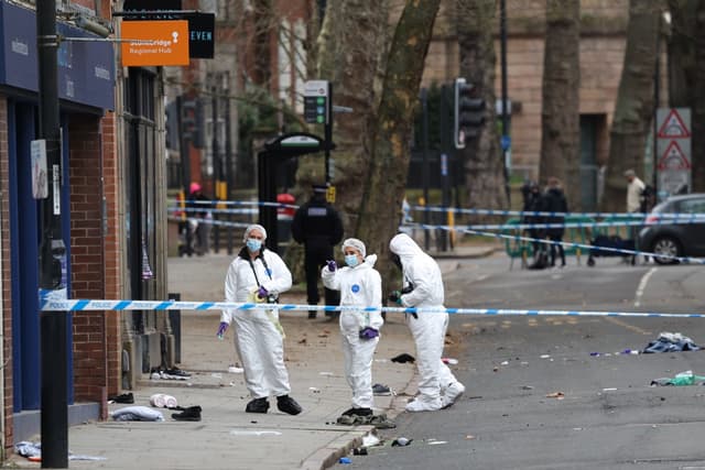 Police forensic officers work amongst a variety of personal items seen covering the road, inside a cordon set up on Friar Gate in central Derby, central England, on March 29, 2026, following an incident the night before where a vehicle was driven into ped
