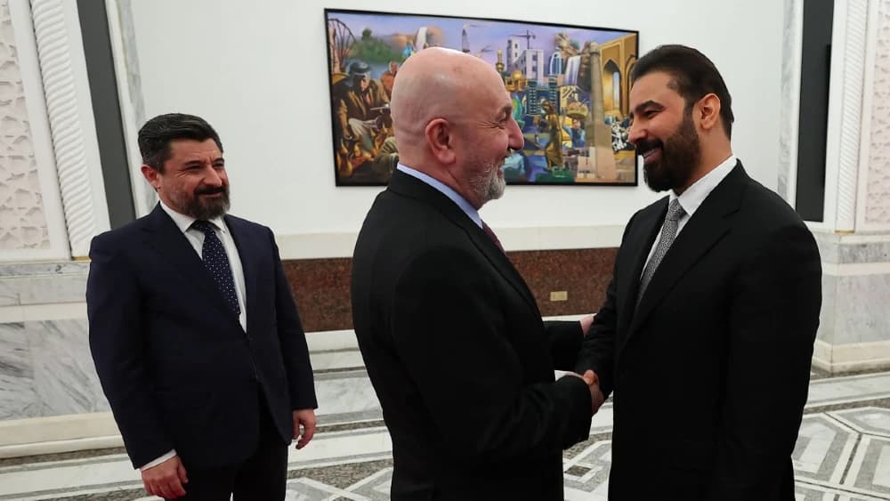 This handout photograph taken and released by the Iraqi Presidency Press Office on April 27, 2026, shows Iraq's President Nizar Amede (C) shaking hands with the newly elected Iraq's Prime Minister Ali al-Zaidi (R), at the Presidential Palace in Baghdad. (