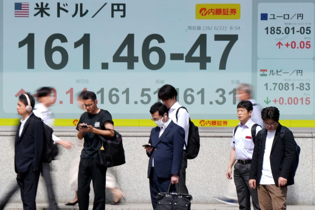 Pedestrians stand in front of electronic boards displaying the foreign exchange rate of the Japanese yen against the US dollar (L) and other currencies (R), along a street in Tokyo on June 22, 2026. (Photo: AFP)