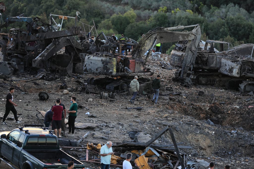 People gather at a site that sold heavy machinery, where a large number of vehicles were destroyed in Israeli airstrikes, in the southern village of Msayleh, Lebanon. (AP)