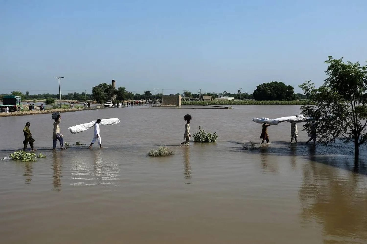 Flood-affected people carry makeshift tents as they wade through floodwaters at Alipur in the Muzaffargarh district of Punjab province on September 13, 2025. (File photo: AFP)