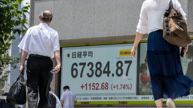 Pedestrians walk past an electronic quotation board displaying the Nikkei Stock Average on the Tokyo Stock Exchange in Tokyo on July 22, 2026. (File photo: AFP)