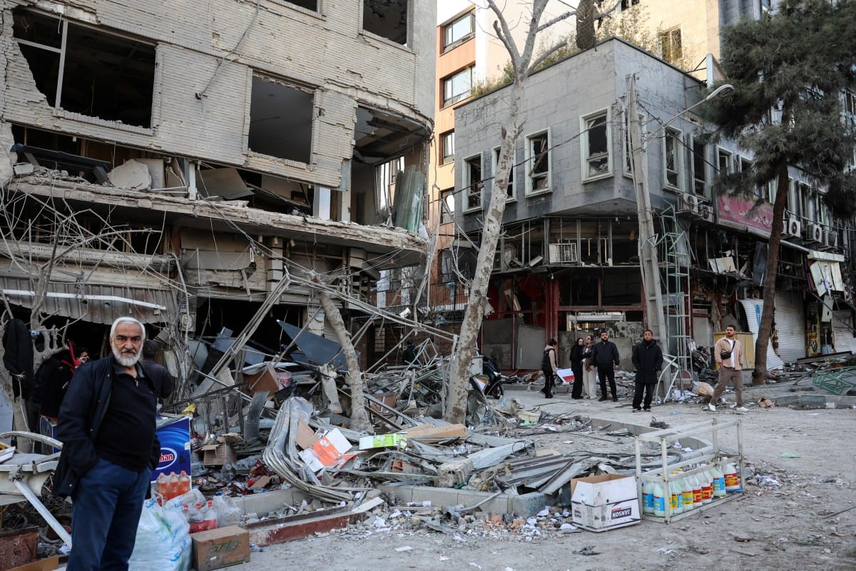Residents stand on a street beside damaged residential buildings near Niloufar square in Tehran during the ongoing joint US-Israeli military campaign on Iran on March 2, 2026. (AFP)