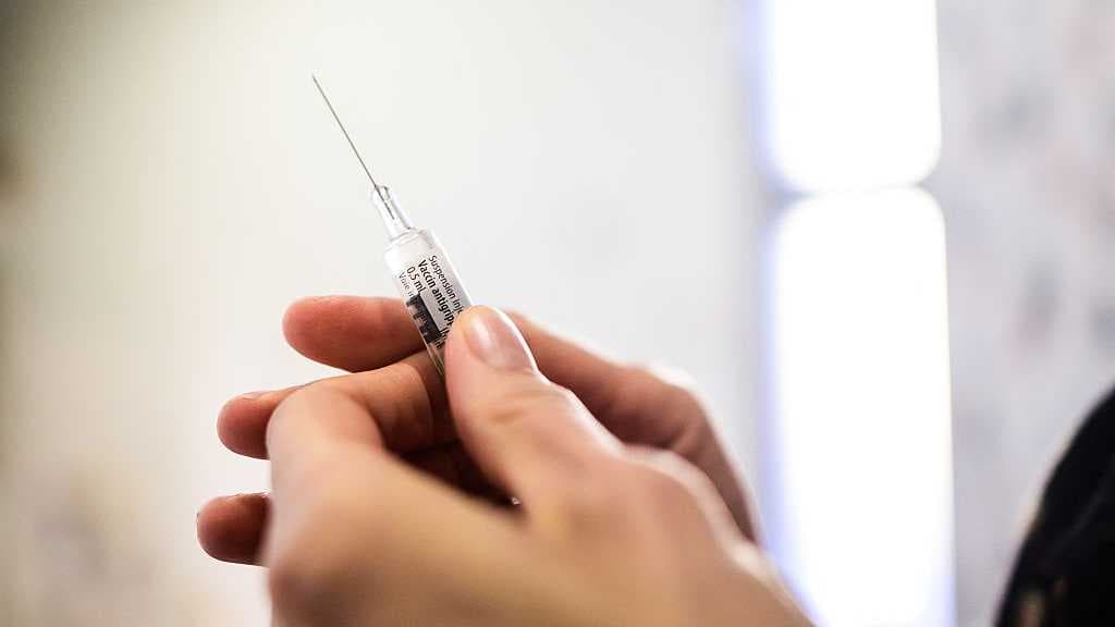 Close-up view of a pharmacist s hand holding a pre-filled syringe of flu vaccine before injection in a pharmacy in Pau, France, on December 8, 2025. (AFP)